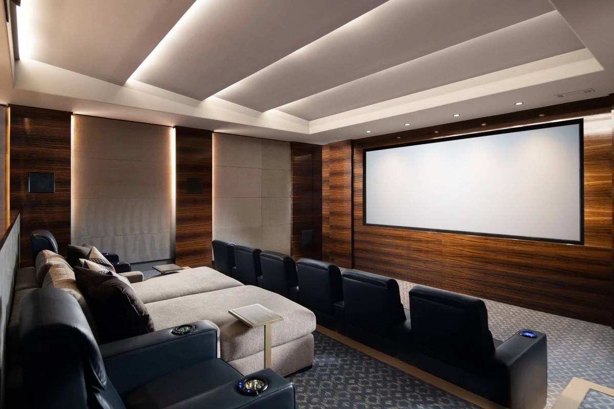 Coastal Club — home theater with exotic wood panels and cove lighting